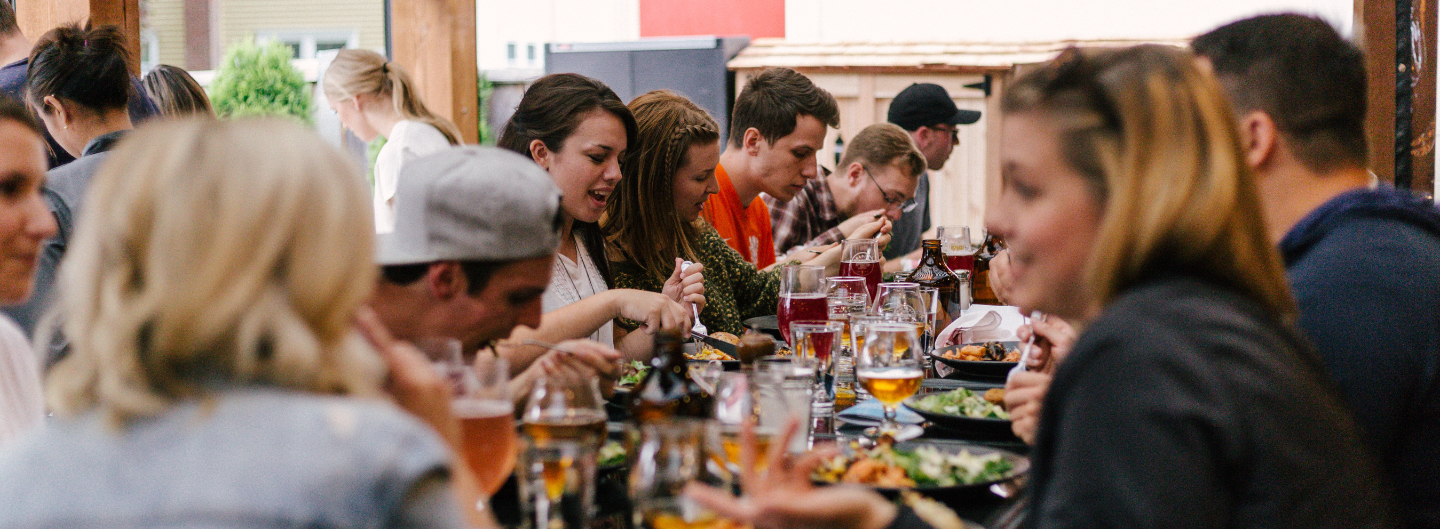 Menschen sitzen am Tisch, essen, bringen und unterhalten sich